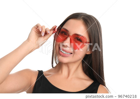 Beautiful young woman wearing heart shaped sunglasses on white background Beautiful young woman wearing heart shaped sunglasses on white background 96740218