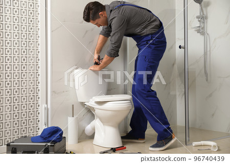 Professional plumber working with toilet bowl in bathroom 96740439