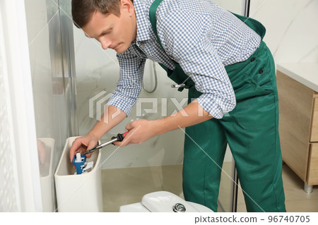 Professional plumber repairing toilet tank in bathroom 96740705