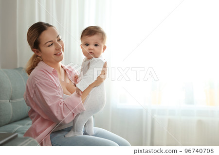 Young woman with her cute baby at home. Space for text 96740708