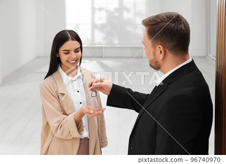 Real estate agent giving key to client in new apartment 96740970