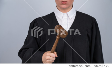 Faceless female judge in a robe holding a court gavel. Faceless female judge in a robe holding a court gavel. 96741579