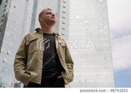 A pensive man stands against the backdrop of a skyscraper. A pensive man stands against the backdrop of a skyscraper. 96741632