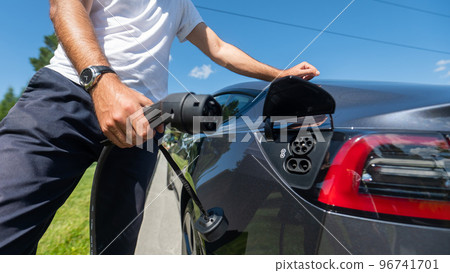 Caucasian man connect charger to electric car.  96741701