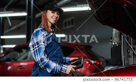 Caucasian female auto mechanic uses a special computer to diagnose faults.  96741755