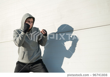 Caucasian man in hoodie is training boxing outdoors. Caucasian man in hoodie is training boxing outdoors. 96741808