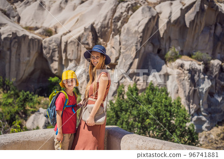 Mom and son tourists exploring valley with rock formations and fairy caves near Goreme in Cappadocia Turkey 96741881