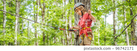 BANNER, LONG FORMAT Happy child in a helmet, healthy teenager school boy enjoying activity in a climbing adventure park on a summer day Portrait of a disgruntled girl sitting at a cafe table 96742171