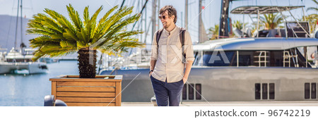 BANNER, LONG FORMAT Man tourist on background of Yacht marina, beautiful Mediterranean landscape in warm colors. Montenegro, Kotor Bay, Tivat city. Porto Montenegro marina view. Go Everywhere. Travel 96742219