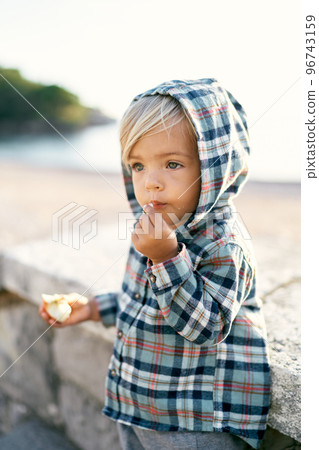 Little girl in a hooded shirt eating an apple on the stone steps. High quality photo Little girl in a hooded shirt eating an apple on the stone steps. High quality photo 96743159