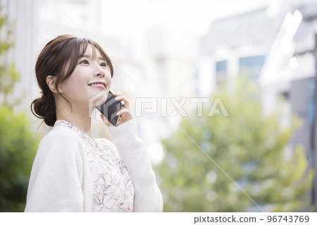 一位年輕女子在街角用智能手機聊天 96743769