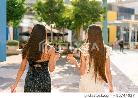Women with takeaway coffee after shopping on street Women with takeaway coffee after shopping on street 96744027