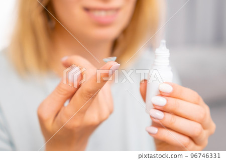 Woman holding contact lens on the finger and eye drop in her hand. Eyecare concept.  96746331