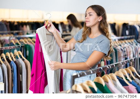 Customer deciding on jersey cardigan in women cloths shop 96747304