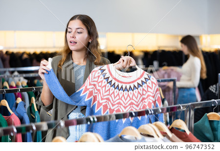 Young woman choosing knitted sweater in store Young woman choosing knitted sweater in store 96747352