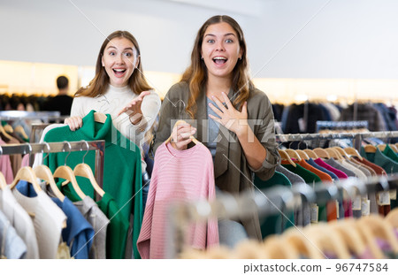 Happy girls pointing finger at new clothes in clothing store Happy girls pointing finger at new clothes in clothing store 96747584
