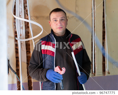 Electrician with cable duct in hands looking at camera 96747775