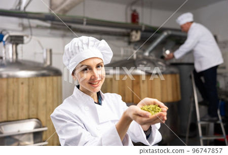 Smiling female brewmaster holding handful of pelletized hops 96747857