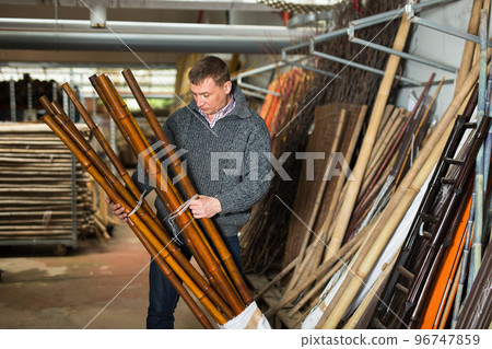 Man chooses decorative fence from bamboo in store 96747859