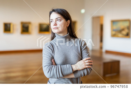 Brunette admiring artworks at paintings exposition in museum Brunette admiring artworks at paintings exposition in museum 96747958