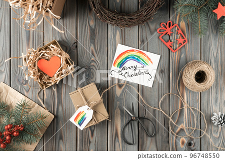 Composition of present box in packaging paper, box with heart and rainbow label, festive card merry Christmas. Holidays Composition of present box in packaging paper, box with heart and rainbow label, festive card merry Christmas. Holidays 96748550