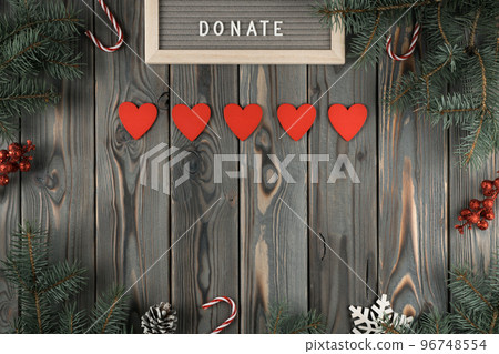 Donation abstract composition with red heart garland on dark wooden Christmas decorative background. Charity, donation 96748554