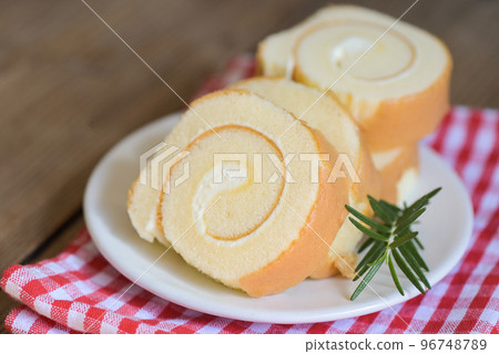 sponge cake roll slices sweets dessert cream roll vanilla snacks and food concept - Swiss Roll Cake, Cake roll on plate cake with rosemary on table 96748789