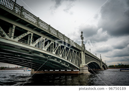 Bridge. A low metal bridge across the river in cloudy weather in gloomy dark colors. St. Petersburg Bridge. A low metal bridge across the river in cloudy weather in gloomy dark colors. St. Petersburg 96750189