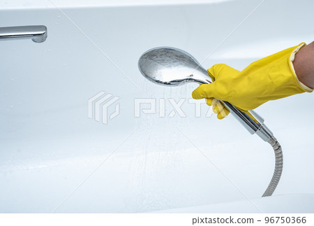 Person using hand held shower head. gloved hand holding shower head. hand holds shower head with pouring water 96750366