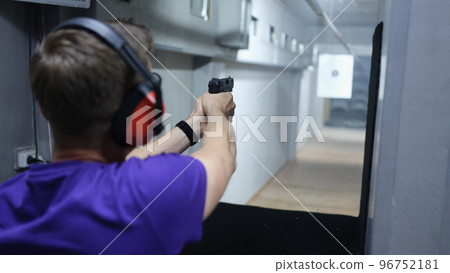 Man shoots at target with pistol in shooting range. 96752181