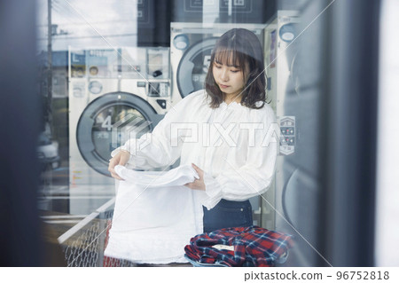 Young woman folding laundry at laundromat 96752818