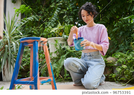 Smiling teenage girl applying blue paint on chair 96753391
