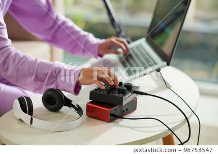 Closeup image of teenager girl setting amplifier plugged in laptop 96753547
