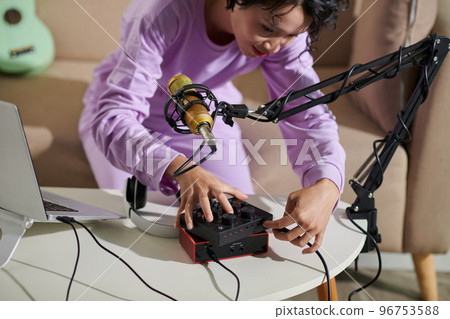 Teenage girl setting equipment for recording podcast at home 96753588