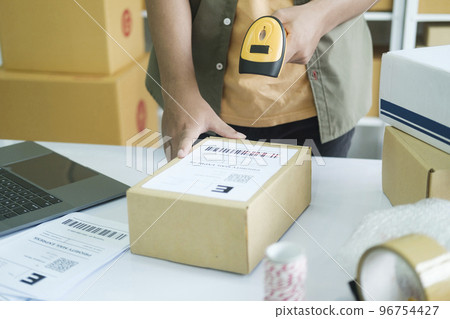Young entrepreneur scanning online order box. 96754427