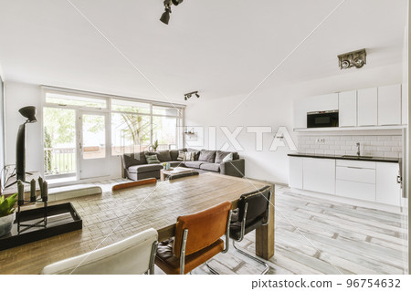 Cozy interior design of living room furnished with comfortable couch and wooden table decorated with carpet and lamp in modern attic apartment with white walls and column 96754632