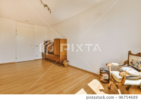 Modern cupboard and vintage chest placed near doors and wicker basket in spacious room with white walls and wooden floor Modern cupboard and vintage chest placed near doors and wicker basket in spacious room with white walls and wooden floor 96754689
