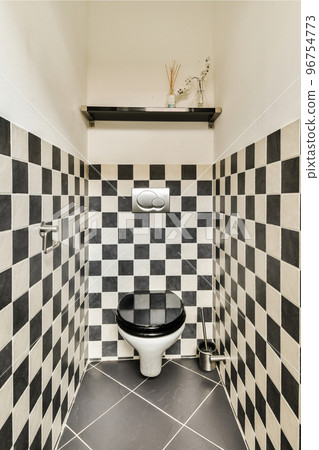 Modern toilet installed on beige wall under button and illuminated shelf in light restroom at home 96754773