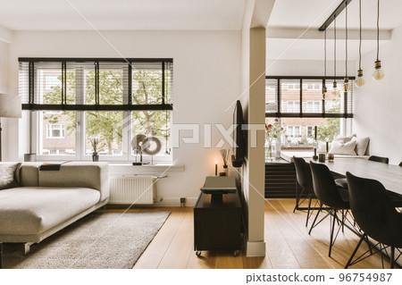 Contemporary minimalist style interior design of light studio apartment with wooden table and chairs in dining zone in living room with white walls and parquet floor 96754987