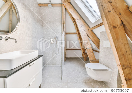 Flush toilet located between sink and shower in small tiled bathroom of contemporary apartment 96755097