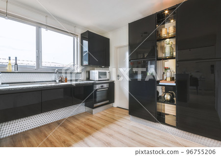 Contemporary minimalist style interior design of light studio apartment with wooden table and chairs in dining zone between open kitchen and living room with white walls and parquet floor Contemporary minimalist style interior design of light studio apartment with wooden table and chairs in dining zone between open kitchen and living room with white walls and parquet floor 96755206