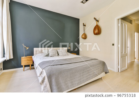 Home interior design of bedroom with bed and wooden wardrobe placed in corner near window in modern apartment 96755318