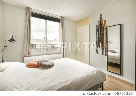 Comfortable bed and cupboard located in near wall with mirror in contemporary bedroom at home 96755356