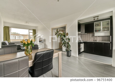 Dark brown cabinets with wooden counter of modern kitchen and dining table set in living room of apartment Dark brown cabinets with wooden counter of modern kitchen and dining table set in living room of apartment 96755400
