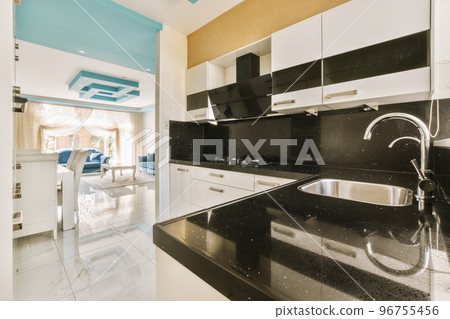 Fragment of interior of light narrow home kitchen with minimalist style white furniture with sink and stove Fragment of interior of light narrow home kitchen with minimalist style white furniture with sink and stove 96755456