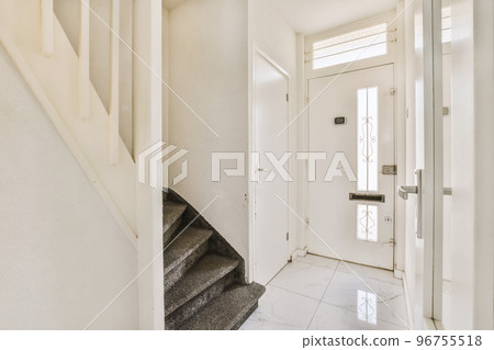 Closed white door of room located near framed pictures and stylish lamp on top of stairway at home Closed white door of room located near framed pictures and stylish lamp on top of stairway at home 96755518