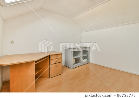 Mansard room with parquet floor and white walls furnished with desk and radiator Mansard room with parquet floor and white walls furnished with desk and radiator 96755775