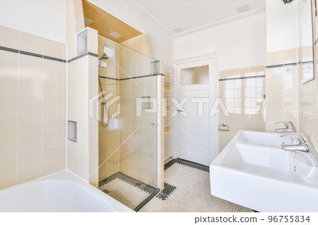 Spacious bathroom with stone sink and mirror on black and white colored tiled wall in expensive apartment 96755834