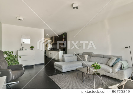Table with chairs and flowers located near lounge area and kitchen in spacious room of contemporary apartment Table with chairs and flowers located near lounge area and kitchen in spacious room of contemporary apartment 96755849