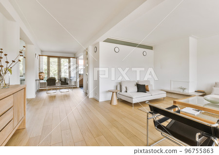 Contemporary minimalist style interior design of light studio apartment with wooden table and chairs in dining zone between open kitchen and living room with white walls and parquet floor Contemporary minimalist style interior design of light studio apartment with wooden table and chairs in dining zone between open kitchen and living room with white walls and parquet floor 96755863
